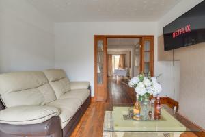 a living room with a couch and a table with flowers at Remarkable 3-Bed House in Middleton Manchester in Manchester