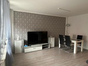 ein Wohnzimmer mit einem TV und einem Tisch mit Stühlen in der Unterkunft Ferienhaus Morgenstern in Wilhelmshaven