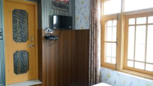 Cette chambre dispose d'une porte, d'une télévision et de deux fenêtres. dans l'établissement Green Resort, à Rājbāgh