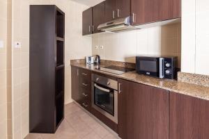 a kitchen with brown cabinets and a counter top with a microwave at Frank Porter - Torch in Dubai