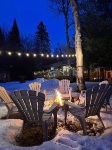 four chairs sitting around a fire in the snow at Private Riverfront Cottage in Muskoka - The MARA in Huntsville