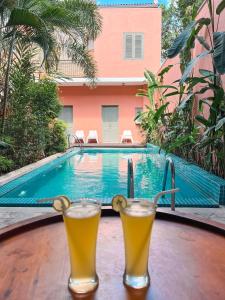 two glasses of beer sitting on a table next to a swimming pool at Angam Villas Colombo in Colombo