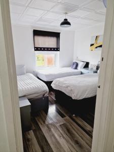 um quarto com três camas e uma janela em 2 Bedroom Cozy Chambers with free parking em Leeds