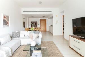 een woonkamer met een witte bank en een tv bij Frank Porter - Al Samar in Dubai