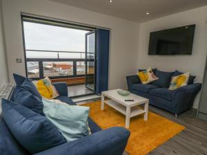 een woonkamer met twee blauwe banken en een tafel bij Wave Song in Hornsea
