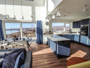 cocina y sala de estar con armarios azules y mesa en 8B Carrigreich, en Tarbert