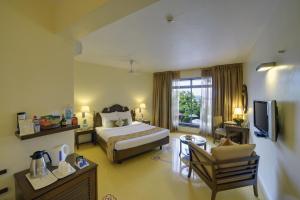 um quarto de hotel com uma cama e uma sala de estar em The Crown Goa em Panaji