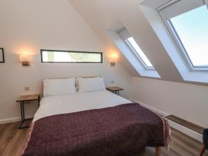 a bedroom with a large bed with two windows at 8B Carrigreich in Tarbert