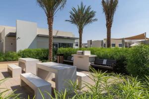 a group of benches and palm trees in front of a building at Frank Porter - Urbana II in Dubai