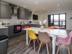 a kitchen with a white table and colorful chairs at Seashell in Hornsea