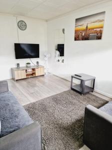 een woonkamer met een tv en een bank bij 2 Bedroom Cozy Chambers with free parking in Leeds