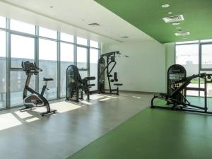 a gym with several tread machines in a room with windows at Frank Porter - Azizi Aura in Dubai
