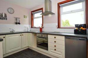 a kitchen with white cabinets and a stove top oven at Rowan Cottage in Blairmore