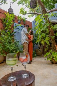a man and a woman standing in a courtyard with wine glasses at Le Muuch Hotel Boutique in Valladolid