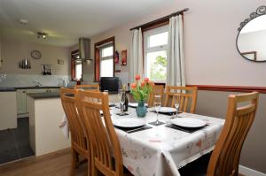 ein Esszimmer mit einem Tisch und Stühlen sowie eine Küche in der Unterkunft Rowan Cottage in Blairmore + 7 Fotos