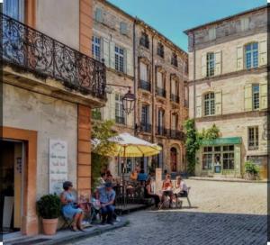 a group of people sitting at a table in front of a building at Location appartement estivale in Montagnac