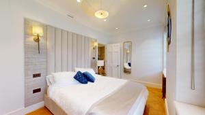 a bedroom with a white bed with blue pillows on it at The Wimpole IX - 1 bed flat in London