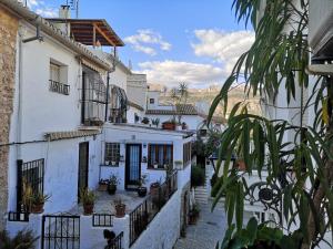 Une allée avec des bâtiments blancs et des plantes en pot dans l'établissement La Casa del Artista, à Altea