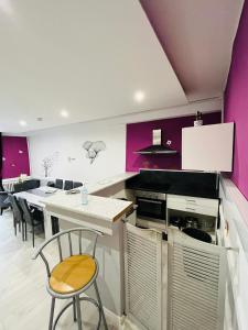 a kitchen with purple walls and a table and chairs at Ludotel in Belley +27 photos