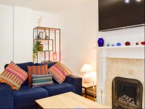 a living room with a blue couch and a fireplace at Buxton Mews in Ulverston