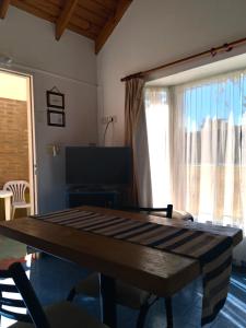 a living room with a table and a large window at Cabañas La Felicidad in Sierra de la Ventana