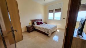 a bedroom with a bed and a window and a television at Appartement centre de Taghazout 2 -WiFi in Taghazout
