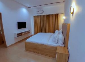 1 dormitorio con 1 cama y TV en Greywood Hotel and Apartments, en Ikeja