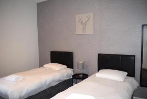Cette chambre comprend 2 lits et une photo murale. dans l'établissement Kelpies Serviced Apartments McDonald- 2 Bedrooms, à Falkirk