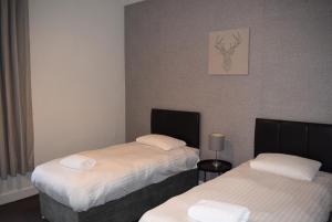 um quarto com duas camas com lençóis brancos em Kelpies Serviced Apartments McDonald- 2 Bedrooms em Falkirk