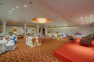 un salón de banquetes con mesas y sillas y una lámpara de araña en The Crown Goa, en Panaji