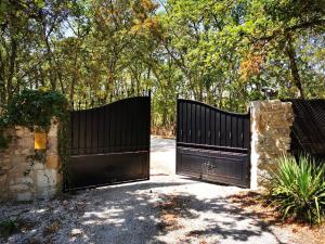 dois portões numa entrada com árvores ao fundo em Les chambres du Presbytère em Montagudet