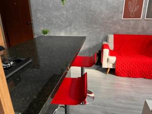 a kitchen with a black table and red chairs at Loft Calmo ao lado do Shopping in Brasilia