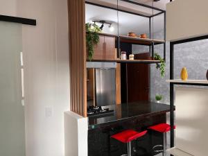 a kitchen with a counter and two red stools at Loft Calmo ao lado do Shopping in Brasilia