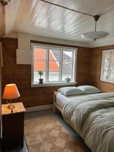 1 dormitorio con 1 cama y 1 mesa con lámpara en Elins gjestehus, en Egersund