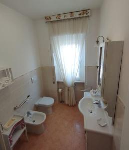 een badkamer met 2 wastafels, een toilet en een raam bij Casa MaVì, la tua casa vacanze in Lanciano