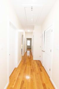 an empty hallway of an apartment with white walls and wood floors at Elegant Modern 3-Bed Apt near NYC in Jersey City