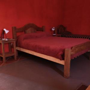 a bedroom with a wooden bed with a red bedspread at Hostal La Casa in Aicuña