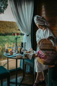 a woman sitting at a table with a basket at Pousada Capanna del Vale - Vale dos Vinhedos in Bento Gonçalves