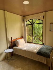 1 dormitorio con cama y ventana grande en Hospedaje Kukul San Vito, en San Vito