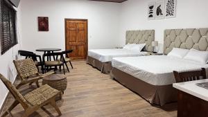 AhuachapánにあるTermales la Montaña “Suite Aire de Montaña 1”のベッド2台、テーブルと椅子が備わるホテルルームです。
