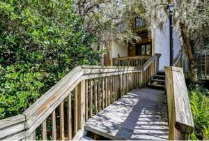 a wooden walkway leading to a house with trees at Beach Escape, 1 block from the Beach in Fernandina Beach
