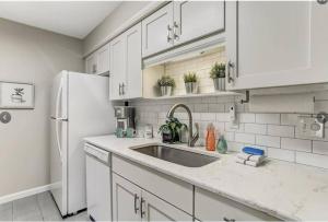 a white kitchen with a sink and a refrigerator at Beach Escape, 1 block from the Beach in Fernandina Beach