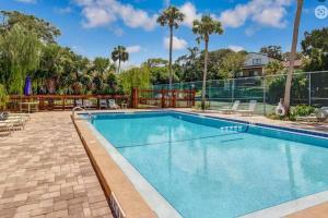a swimming pool at a resort with palm trees at Beach Escape, 1 block from the Beach in Fernandina Beach