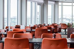 Best Western Plus Hotel Ilulissat في إيلوليسات: غرفة فارغة فيها طاولات وكراسي ونوافذ