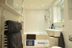uma casa de banho branca com um lavatório e um espelho em Beautiful Apartment Next To LGI By Movida Property Group Short Lets & Serviced Accommodation em Leeds
