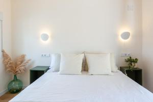 1 dormitorio con 1 cama blanca grande con almohadas blancas en La Casita del Malecón en Murcia