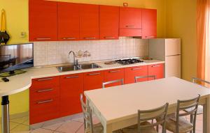 une cuisine avec des placards rouges et une table avec des chaises dans l'établissement Mara 12, à Rosolina Mare