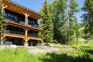 a large log house with a deck in the woods at LUXURY SKI-IN-OUT Mid-Mountain Game Room Hot Tub in Whitefish