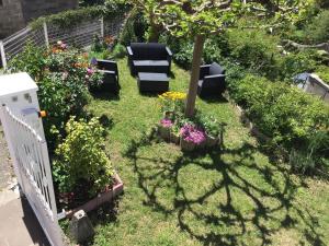 un jardín con sillas, flores y un árbol en Appartement Vals les bains, en Vals-les-Bains