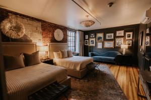 a bedroom with two beds and a couch and a brick wall at HATCHERY HOTEL & EVENT CENTER in La Crosse